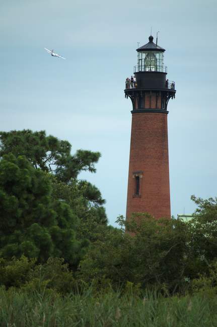 A plane flies in the distance while tourists look on